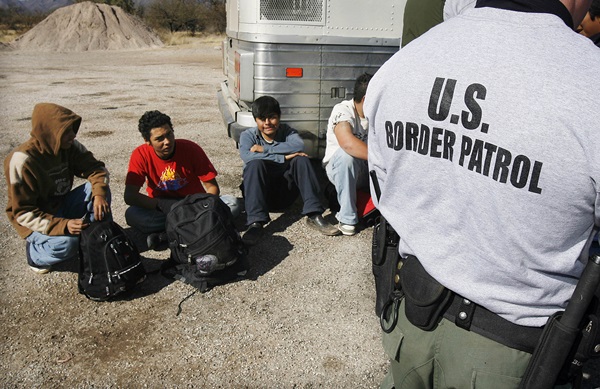 FILE - In this Jan. 19, 2007 file photo, the U.S. Border Patrol detains a large group of suspected immigrants at the Arizona-Mexico border in Sasabe, Ariz. A federal judge has barred use of a policy that allowed people who paid to be sneaked into the United States to be charged under Arizonas immigrant smuggling law as conspirators to the crime. U.S. District Judge Robert Broomfields ruling said the interpretation of the 2005 state law conflicts with federal law. The ruling is the latest in a series of restrictions placed on Maricopa County Sheriff Joe Arpaios immigration enforcement efforts. (AP Photo/Ross D. Franklin, File)