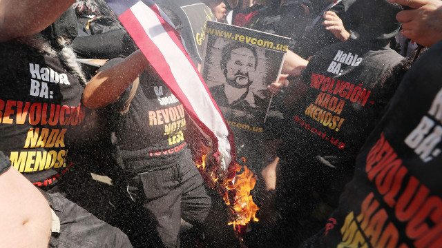 CLEVELAND, OH - JULY 20: A group tries to burn an American Flag as police move in near the sight of the Republican National Convention (RNC) in downtown Cleveland on the third day of the convention on July 20, 2016 in Cleveland, Ohio. Many people have stayed away from downtown due to road closures and the fear of violence. An estimated 50,000 people are expected in Cleveland, including hundreds of protesters and members of the media. The four-day Republican National Convention kicked off on July 18. (Photo by Spencer Platt/Getty Images)